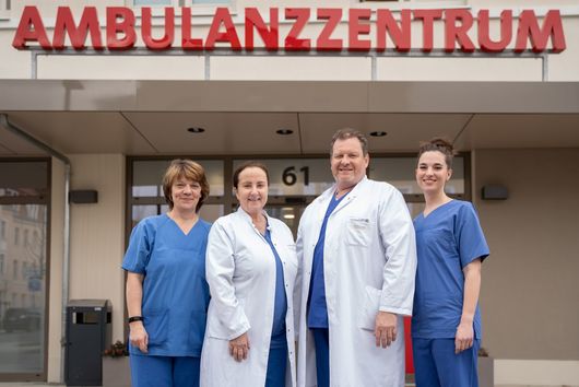 Drei Frauen und ein Mann stehen unter einem Schriftzug Ambulanzzentrum.