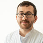 Portrait eines Arztes mit braunen Haaren, kurzem Bart und Brille